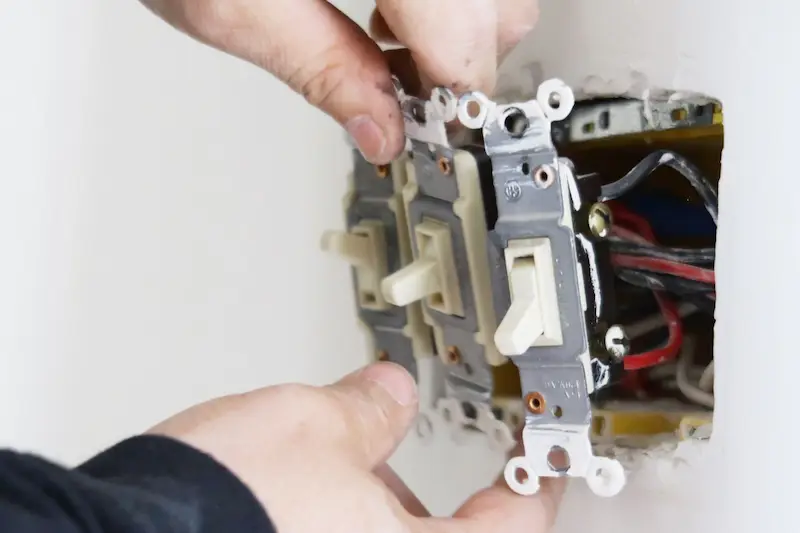 Residential switches being repaired by an electrician in a Kelowna house.
